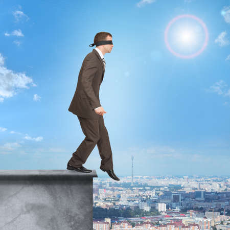 Man walking from edge of building roof with band on his eyesの写真素材