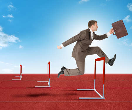 Businessman with suitcase  hopping over treadmill barrierの写真素材