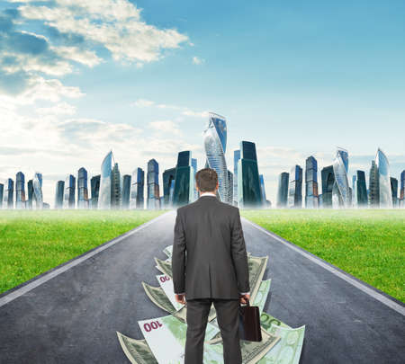 Businessman on money road going to city, rear viewの写真素材