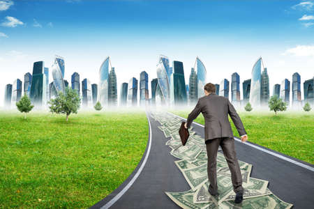 Businessman on money road running to city, rear viewの写真素材