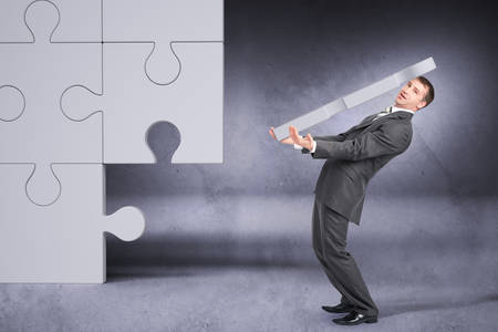 Businessman holding big puzzle piece on grey backgroundの写真素材