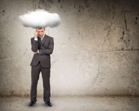 Sad businessman with cloud above head on grey backgroundの写真素材