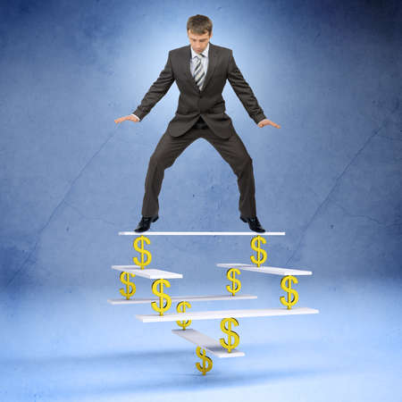 Businessman standing on balance with dollar sign and looking downの写真素材
