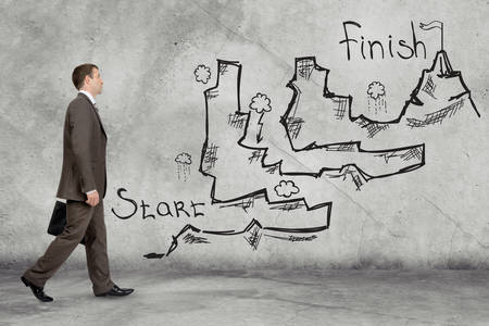 Thoughtful young businessman standing on dark chalkboard background. Concept for successful projectの写真素材