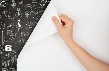 Hand turns page and drawing concept on blackboard with symbolsの写真素材