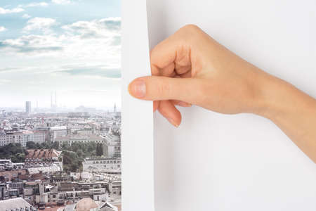 Hand turning page to city with skyscrapers and cityviewの写真素材