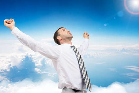 Young businessman enjoing success on blue sky backgroundの写真素材