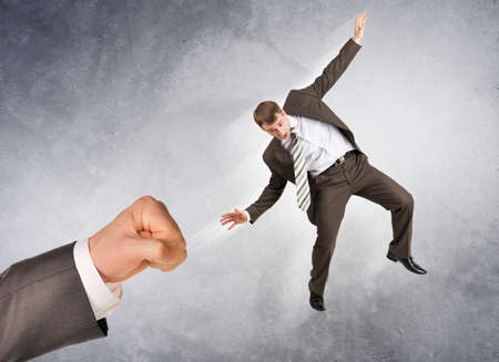 Businessman hitting little man on abstract grey backgroundの写真素材