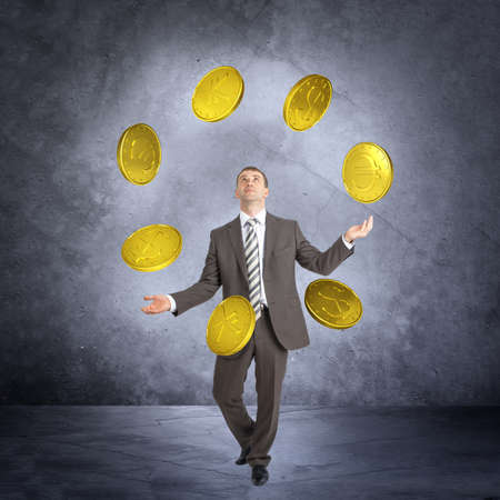 Businessman juggling big coins on abstract grey backgroundの写真素材