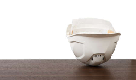 Plastic safety helmet with blueprints on table isolated on white background, closeupの写真素材