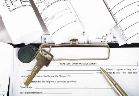 Folder with key and pen on blueprint and blueprint rolls background