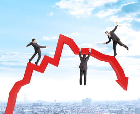 Set of businessmen trying not to fall from arrow on city view backgroundの写真素材