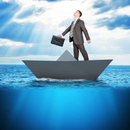 Businessman in paper boat in blue sea, business conceptの写真素材