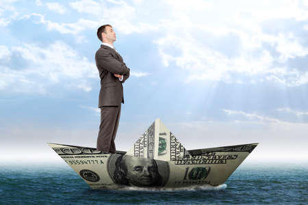 Businessman in dollar boat in blue sea, business conceptの写真素材