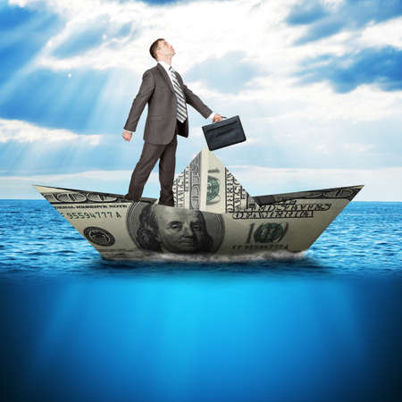 Businessman in dollar boat in blue sea, business conceptの写真素材