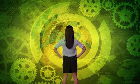 Business woman in front of holographic screen with cog wheelsの写真素材