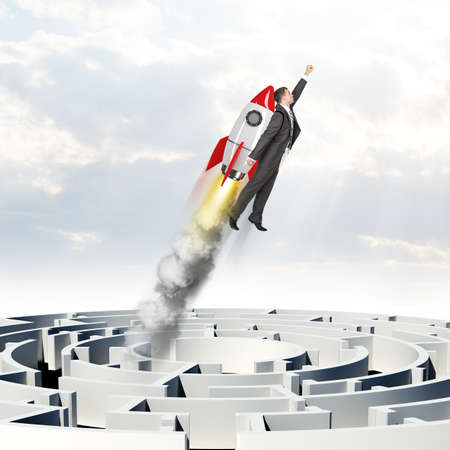Businessman flying up with rocket above labyrinthの写真素材