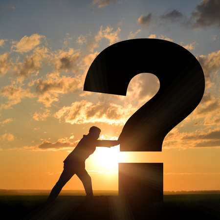 Businessman pushing question mark  on sunset backgroundの写真素材