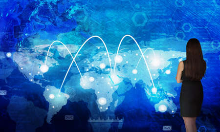 Business woman in front of holographic screen with world mapの写真素材