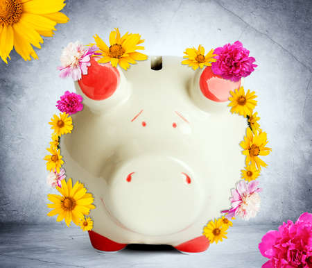 Piggy bank with flowers on grey wall backgroundの写真素材