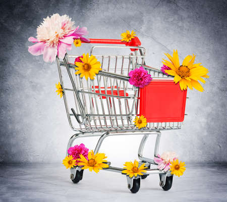 Shopping cart with flowers on grey wall backgroundの写真素材