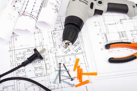 Architecture plan and rolls of blueprints with pliers and electric screwdriver. Building concept