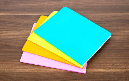 Pile of colorful notebooks on wooden table backgroundの写真素材