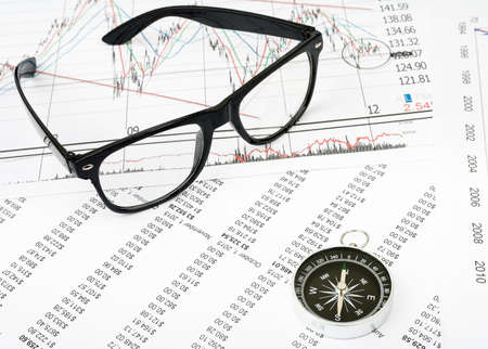 Glasses and compass on grpahical charts background, business conceptの写真素材
