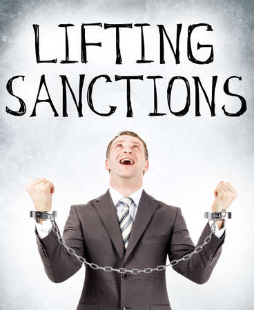 Happy businessman in cuffs looking at lifting sanctions on grey wall backgroundの写真素材