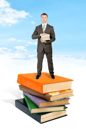 Man stand on pile of book and hold books. Blue sky and cloud at backgroundの写真素材