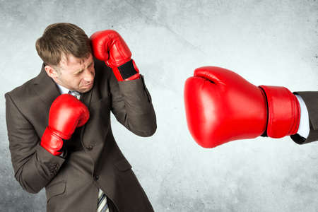 Businessman in boxing gloves against big red boxing gloveの写真素材