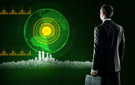 Business man in suit with suitcase stands near virtual screen with city. Rear view
