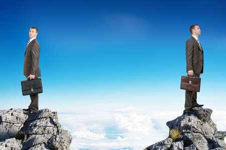 Young businessmen with suitcases standing on peaks with their backs to each otherの写真素材