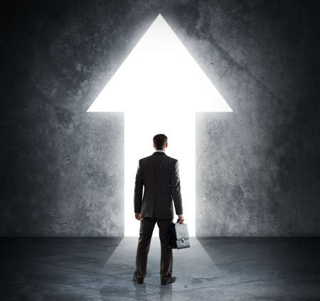 Business person with briefcase and solution arrow on wallの写真素材