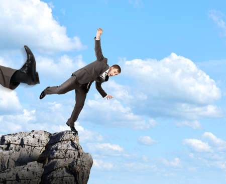 Businessman kicked by his boss big foot from rockの写真素材