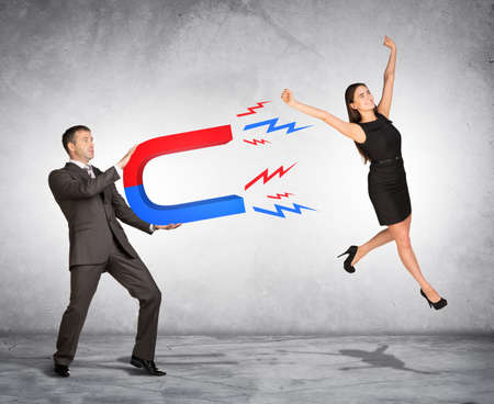 Concept of capturing people with marketing. Businessman attracting woman with magnet