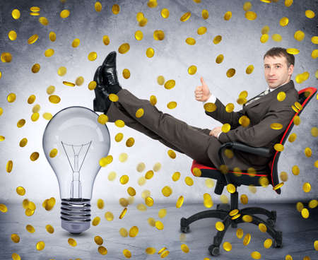 Businessman with light bulb under coin rain, idea is money conceptの写真素材