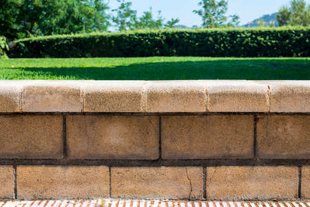 Stone low fence against a background of green lawnの写真素材