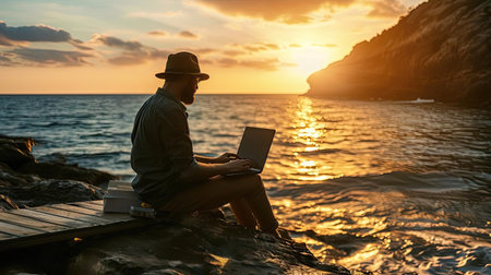 Man on seashore working remotely on computerの素材