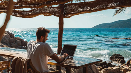 Man on seashore working remotely on computerの素材