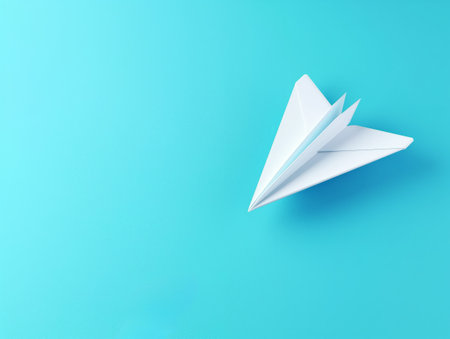 A single white paper plane centered on a vibrant blue background, symbolizing ideas, travel, and creativity.の素材