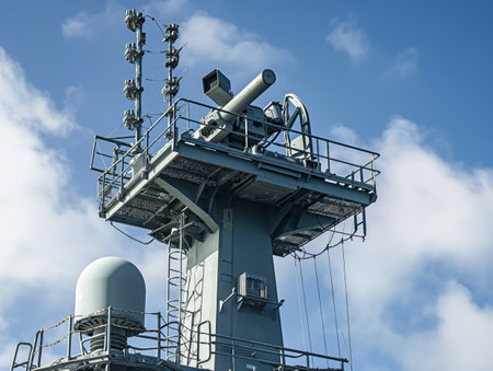 Close-up view of a naval ships radar and communication tower against a clear blue sky.の素材