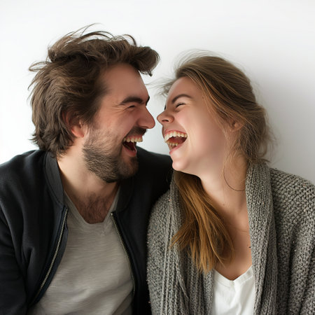 A candid moment of a man and woman sharing a genuine, hearty laugh in a light, minimalist setting.の素材