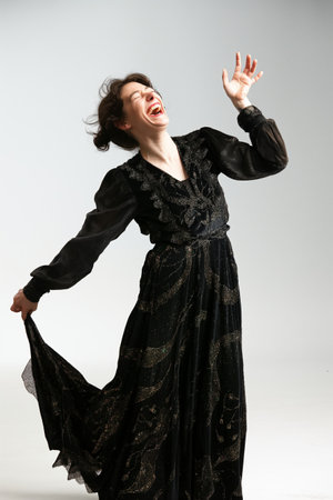 Joyful woman in a black dress laughing with head tilted back, expressing genuine happiness.の素材