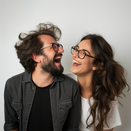 Two people with glasses, laughing heartily with heads tilted togetherの素材