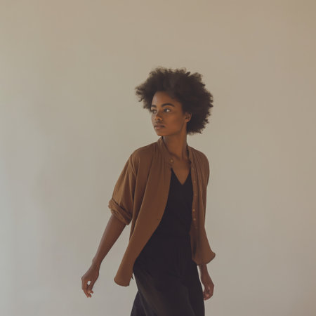A stylish young woman poses with a thoughtful expression against a neutral background.の素材