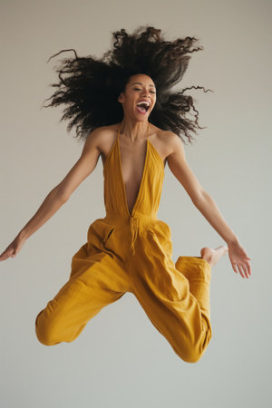 Exuberant woman in mid-jump with hair flying, expressing carefree joy and vitalityの素材