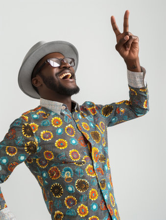 Smiling man in stylish hat and sunglasses poses playfully, making a peace sign.の素材