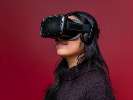 Side profile of a smiling young woman wearing a VR headset against a red background.の素材