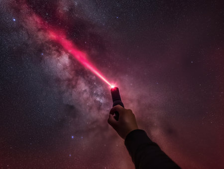A person pointing a laser towards the starry night sky, highlighting the beauty of the cosmos.の素材